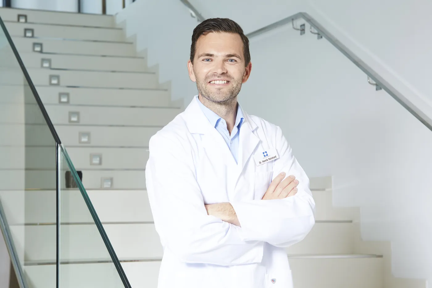 Dr. Henrik Reinhard i hvid kittel på trappen i klinikken